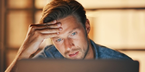 Forvirret mand sidder foran en laptop.